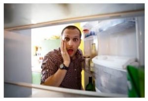 Shocked man looking in his empty fridge.